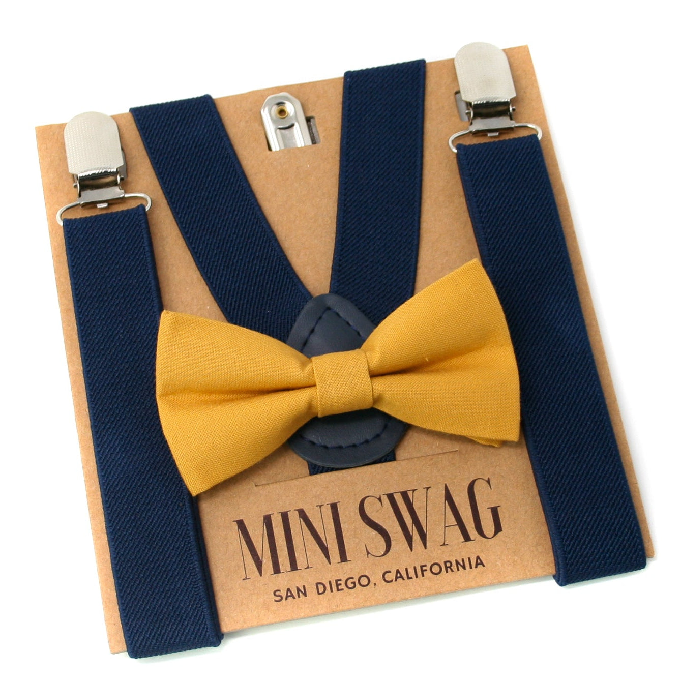 Navy suspenders with a mustard yellow bow tie on a 'Mini Swag' branded card.