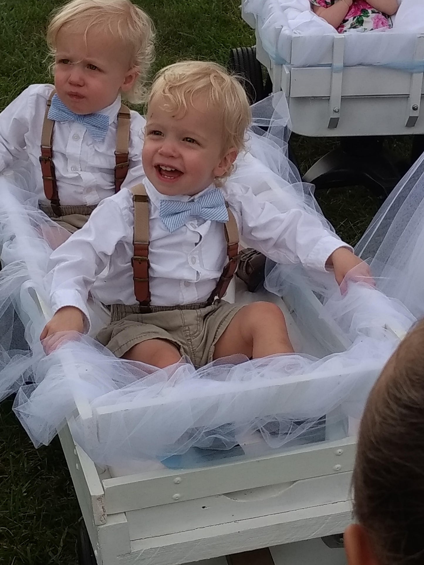 two young boys in tuxedos sitting in a wagon