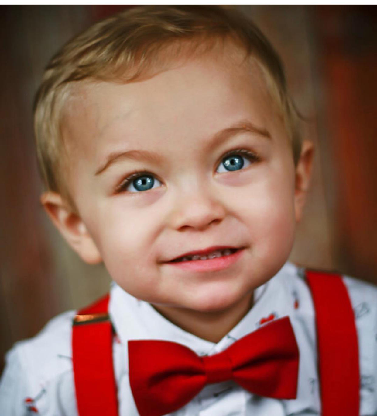 a young boy wearing a red bow tie and suspenders