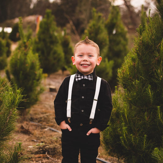 Child in formal attire standing in a field of trees