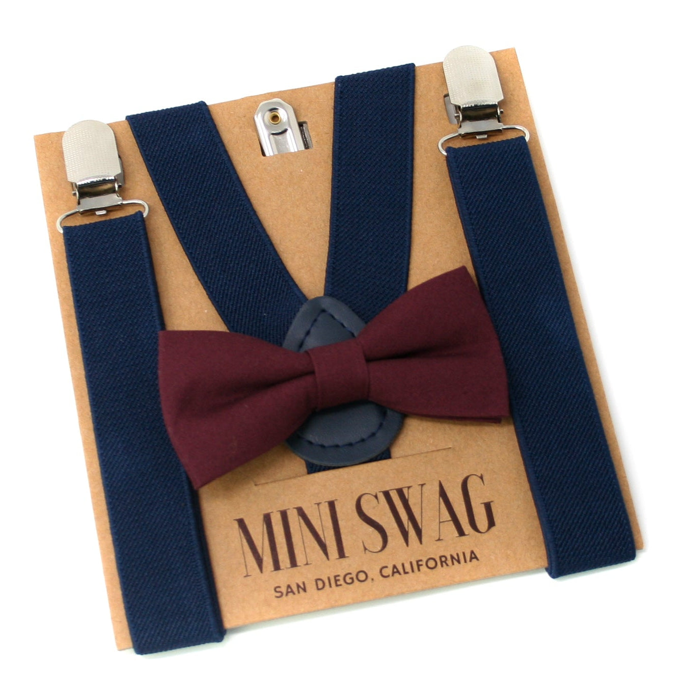 Navy suspenders with a burgundy bow tie on a 'Mini Swag' branded card.
