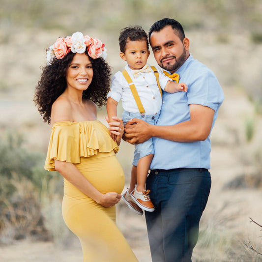 Family of three posing outdoors in a desert-like setting Mustard  yellow bow tie suspenders, pregnancy photo shoot