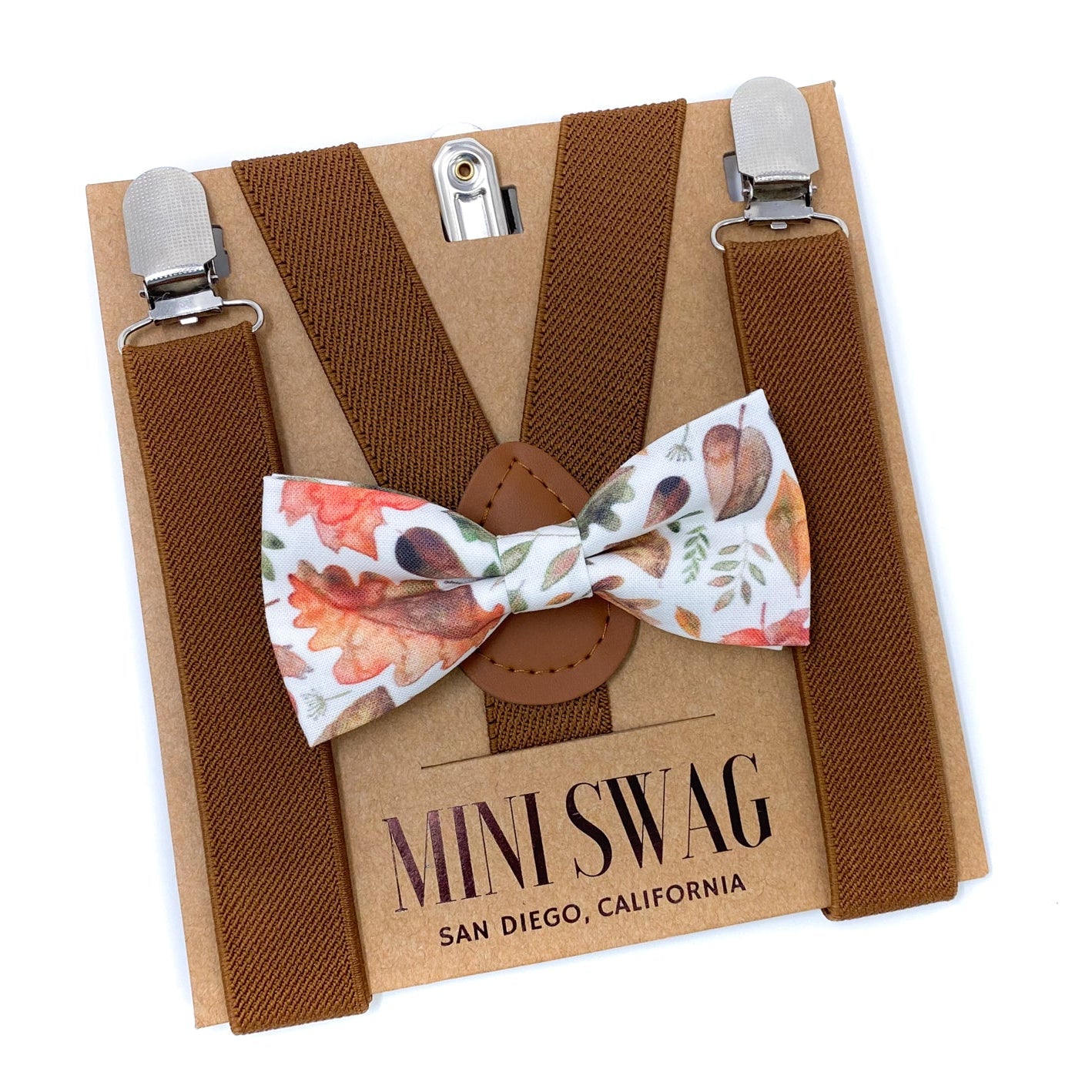 Brown suspenders with a floral bow tie on a 'Mini Swag' branded card.