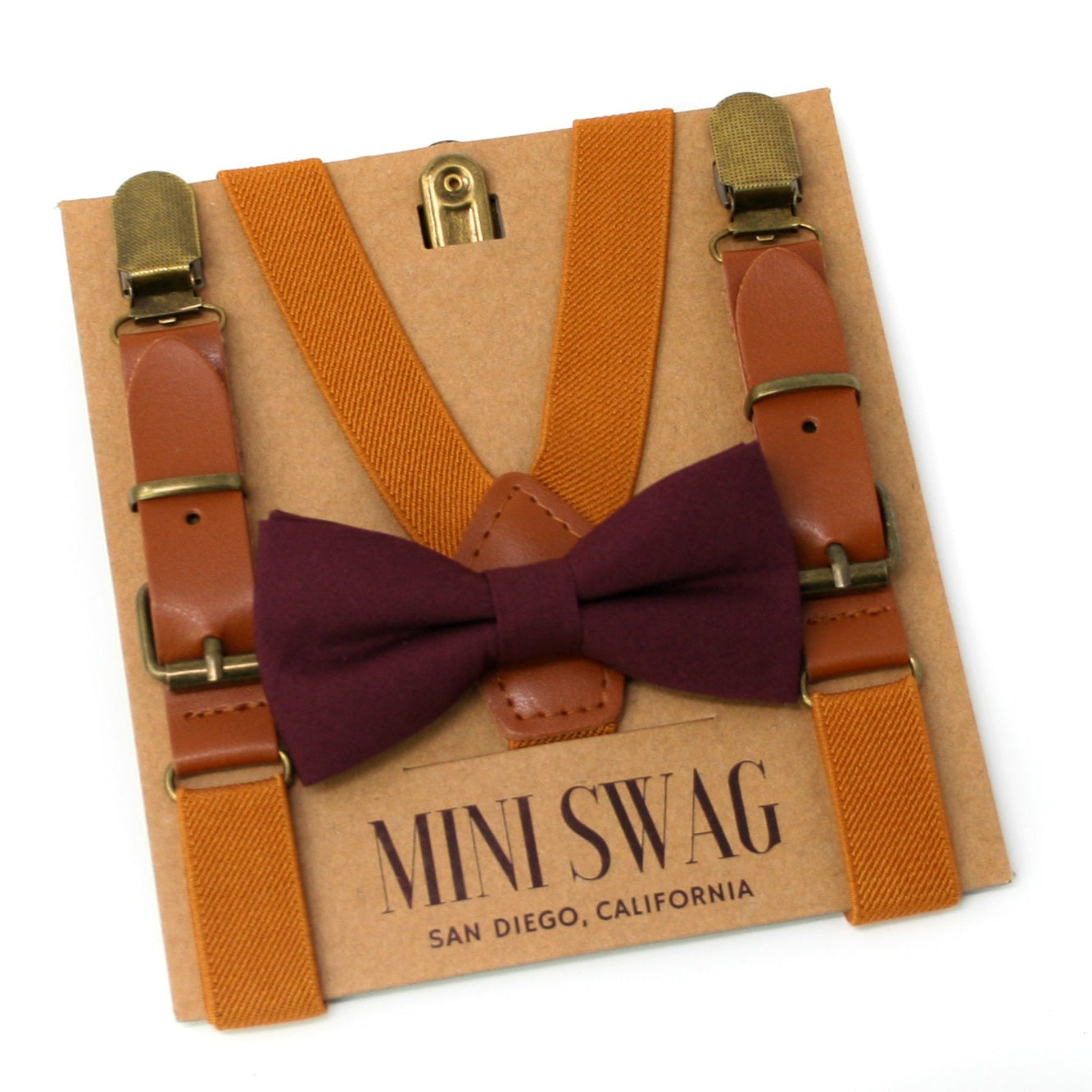 camel leather suspenders with a wine bow tie on a 'Mini Swag' branded card.