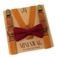 Camel leather buckle suspenders with gold clasps and a Burgundy bow tie on a Mini Swag branded card.