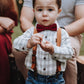 Child wearing suspenders and a Burgundy bow tie with a blurred background