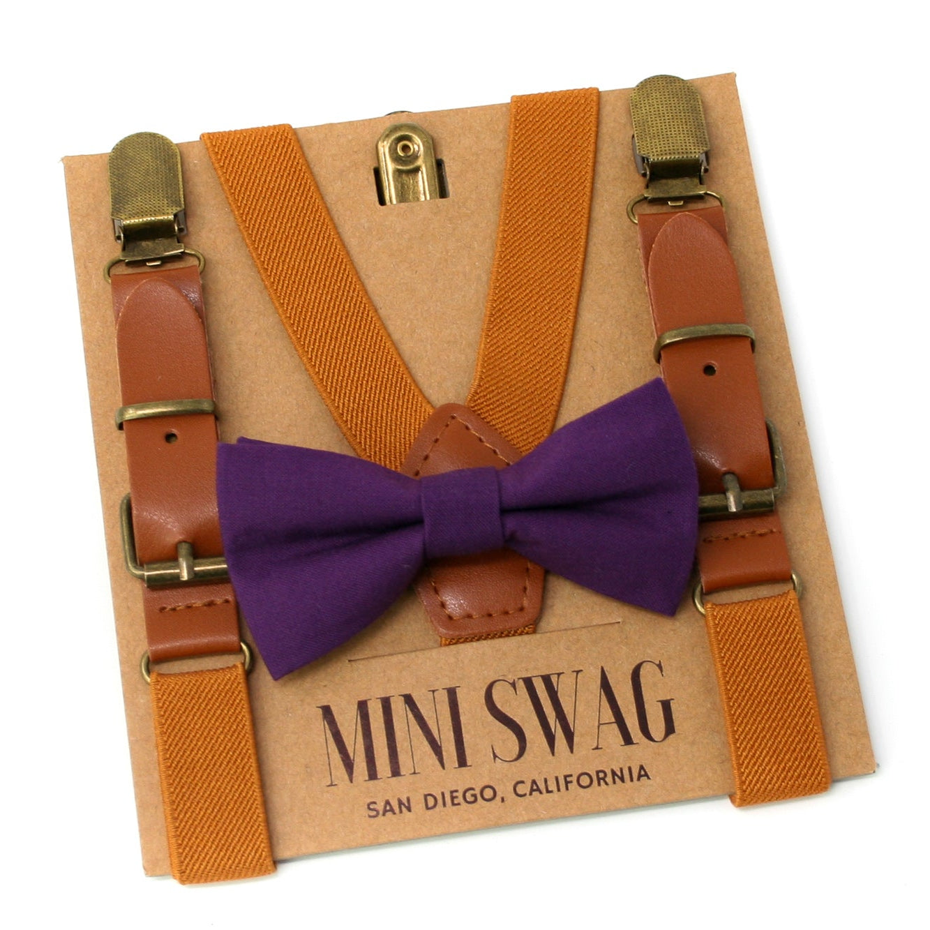 Camel brown suspenders with brown leather straps and a Plum purple bow tie on a 'Mini Swag' branded box.