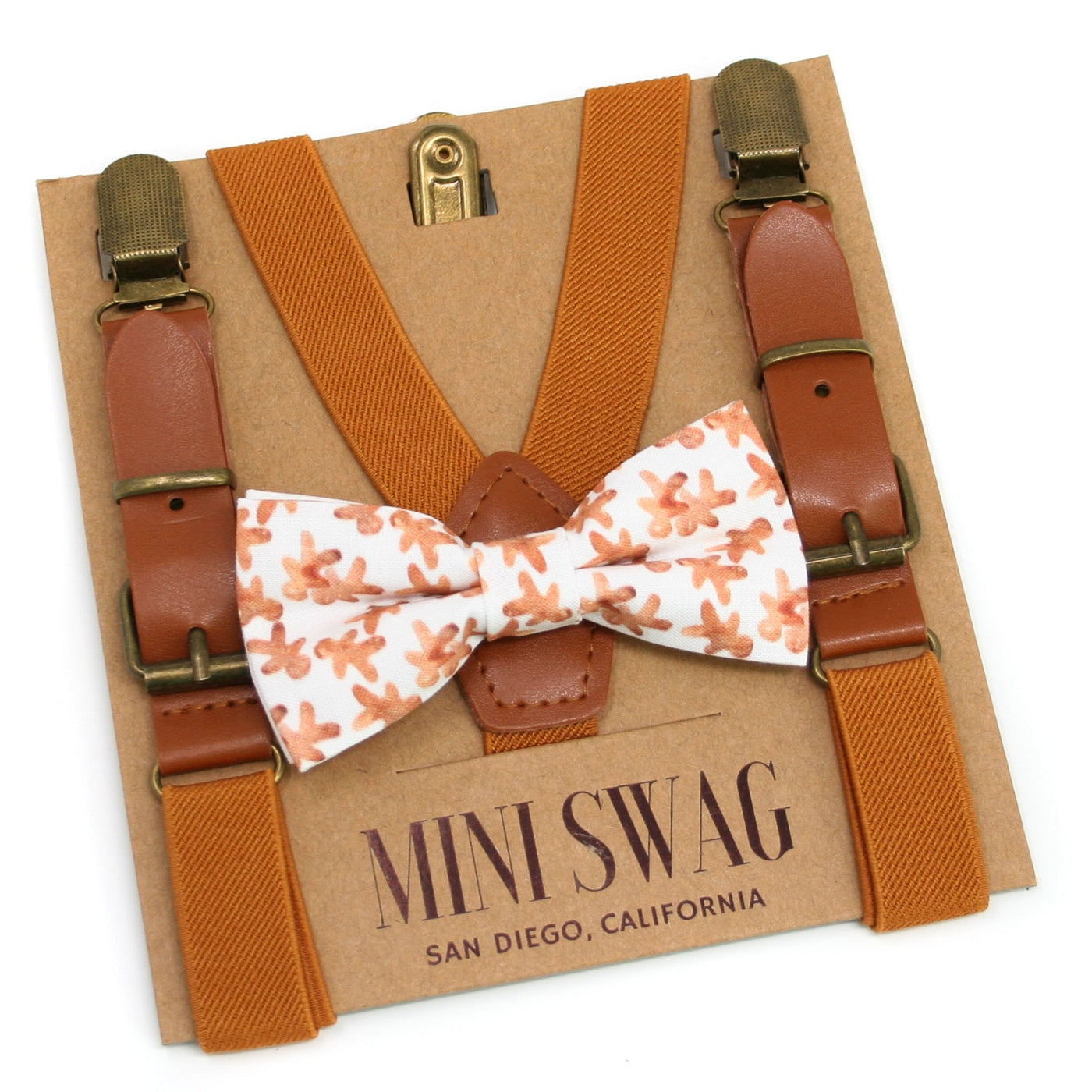 Orange suspenders with a gingerbread bow tie on a 'Mini Swag' branded card.
