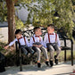 Three young boys ring bearers sitting on a bench wearing matching outfits with suspenders and Cinnamon bow ties.