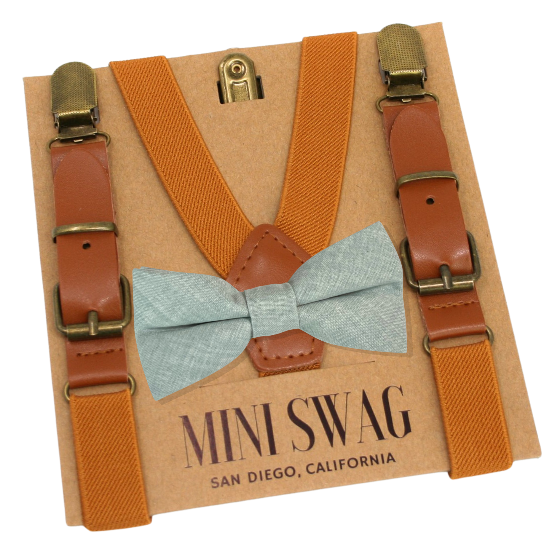 Camel brown suspenders with brown leather straps and a dusty sage bow tie on a 'Mini Swag' branded card.