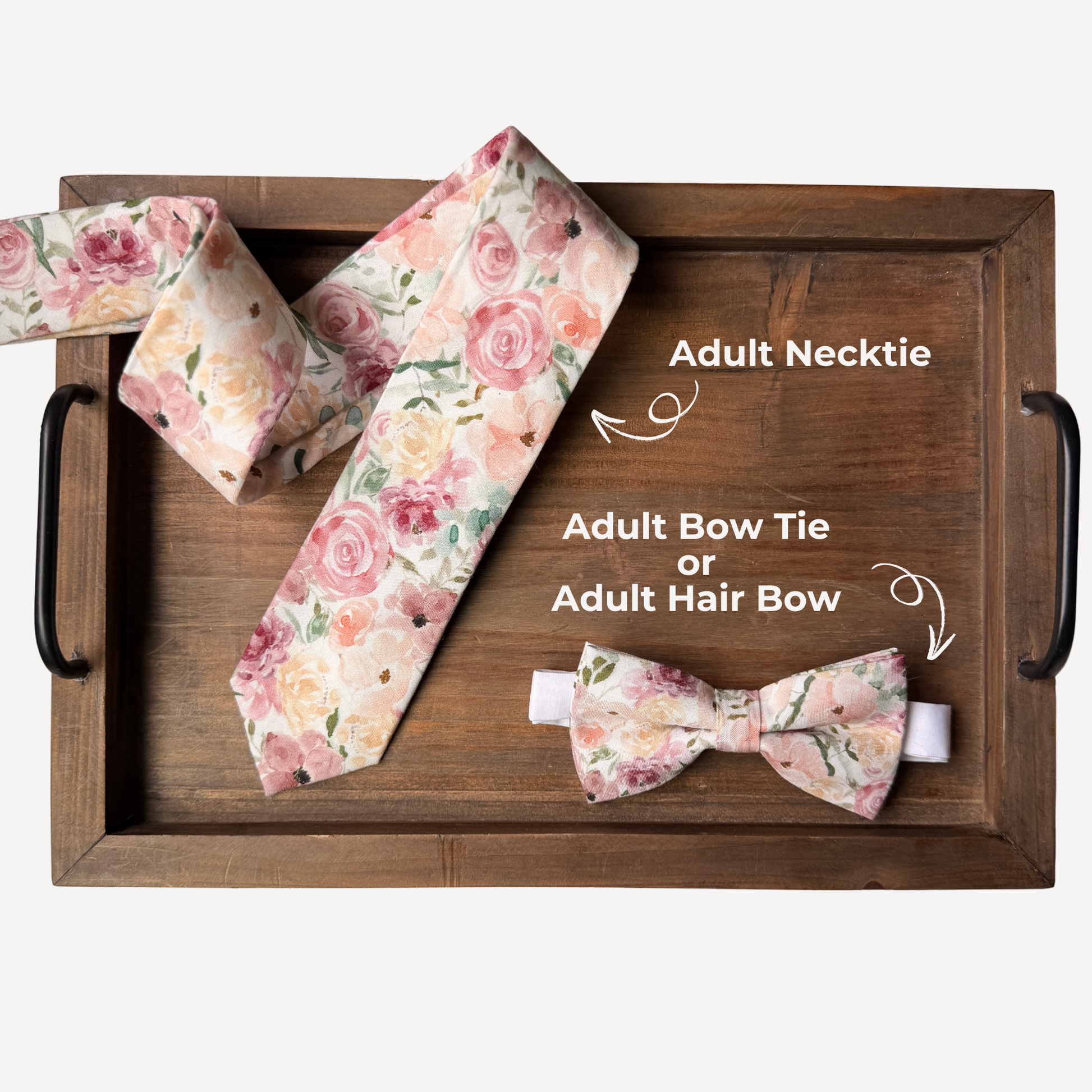 Floral necktie and bow tie set on a wooden tray with text labels.