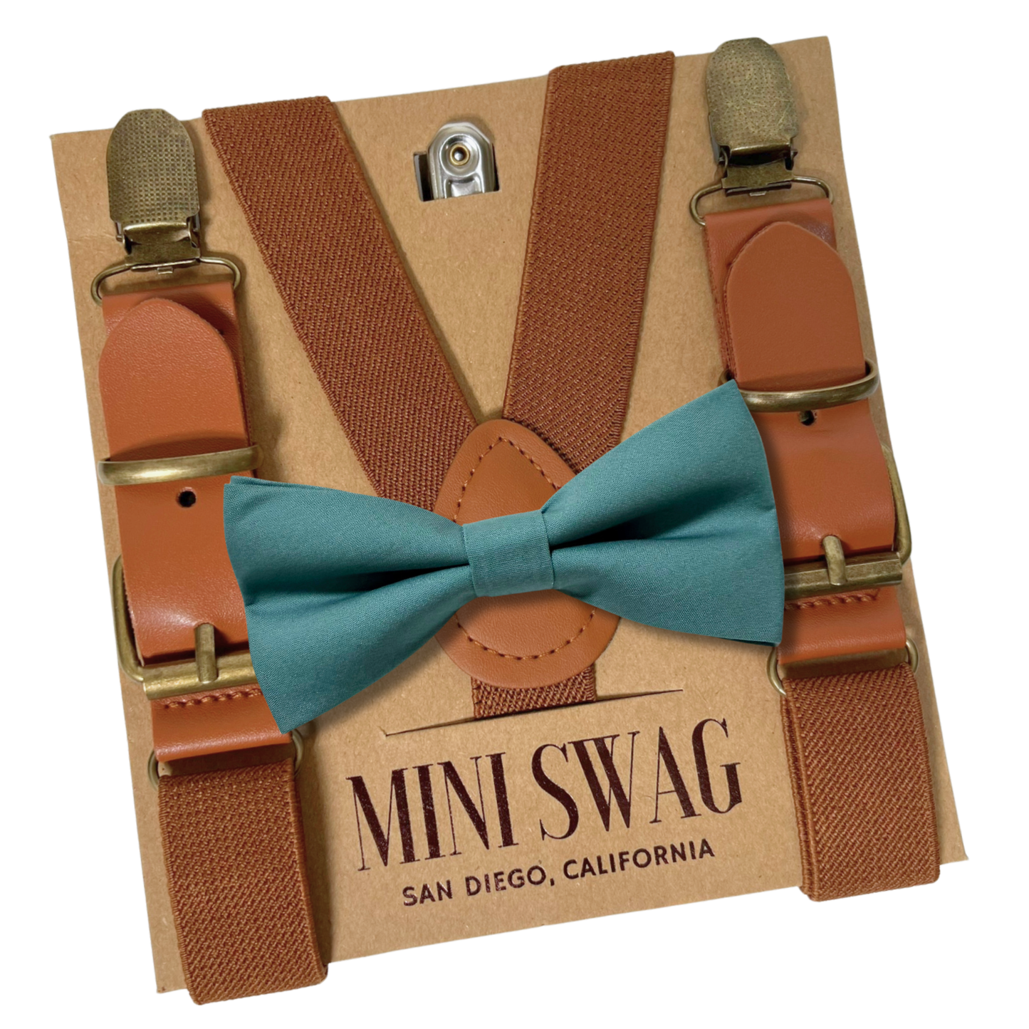Brown leather buckle suspenders with gold clips and a sea glass bow tie on a 'Mini Swag' branded box.
