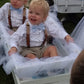two young boys in tuxedos sitting in a wagon