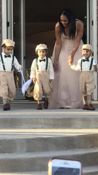 a woman in a white dress and two small ring bearers