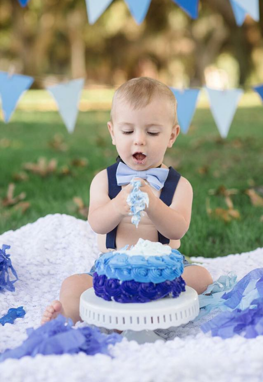 Navy Suspenders with matching navy back patch, and silver hardware, solid light blue bow tie.  Baby birthday smash cake