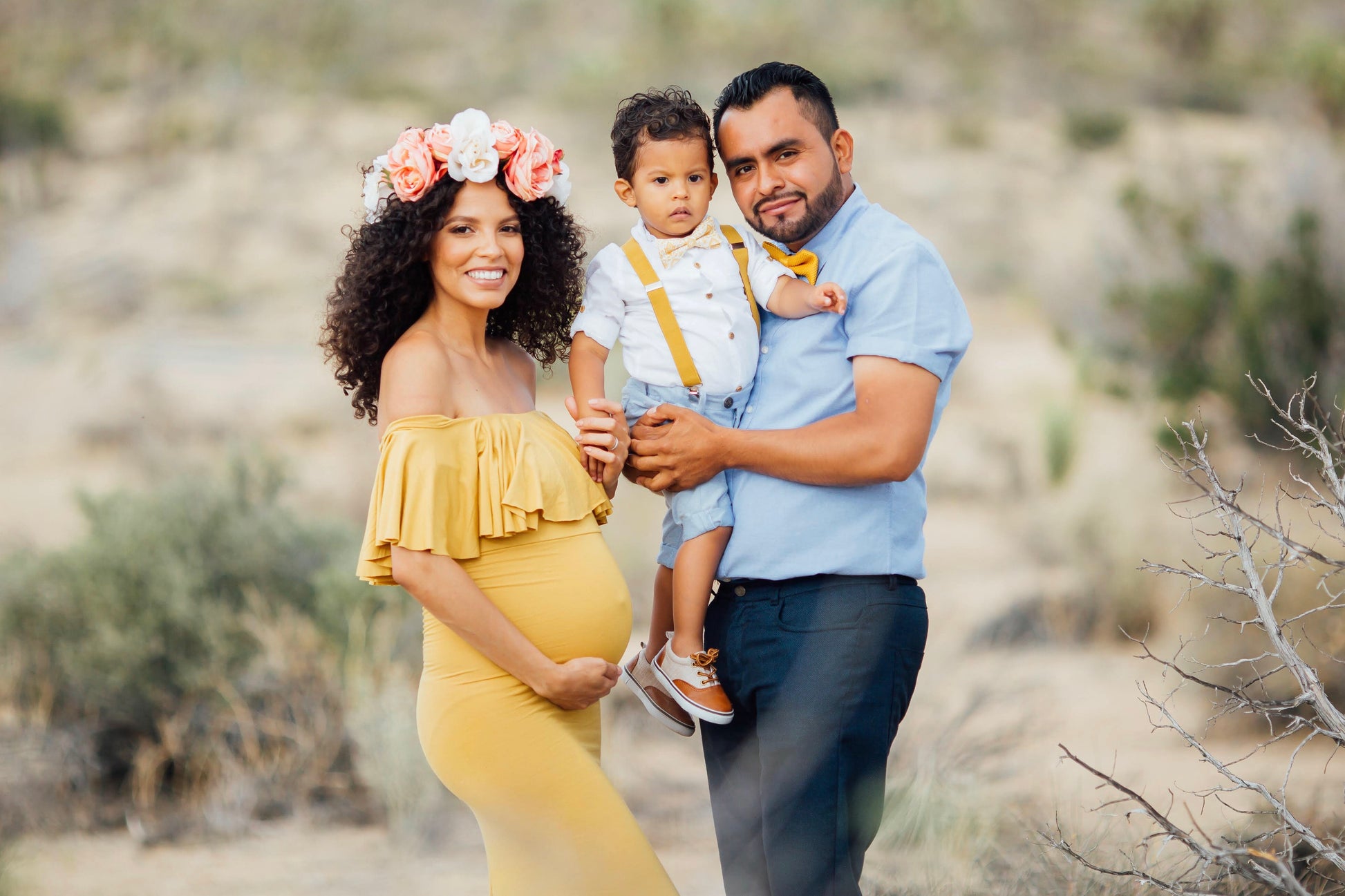 a man and woman holding a baby in a desert